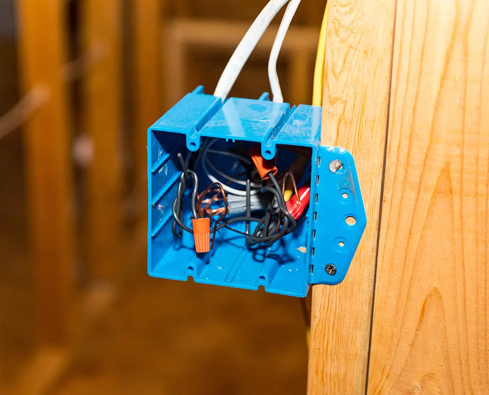 Electrical wiring and wire connectors inside a blue electrical box mounted to a wooden stud in Belleville, IL.